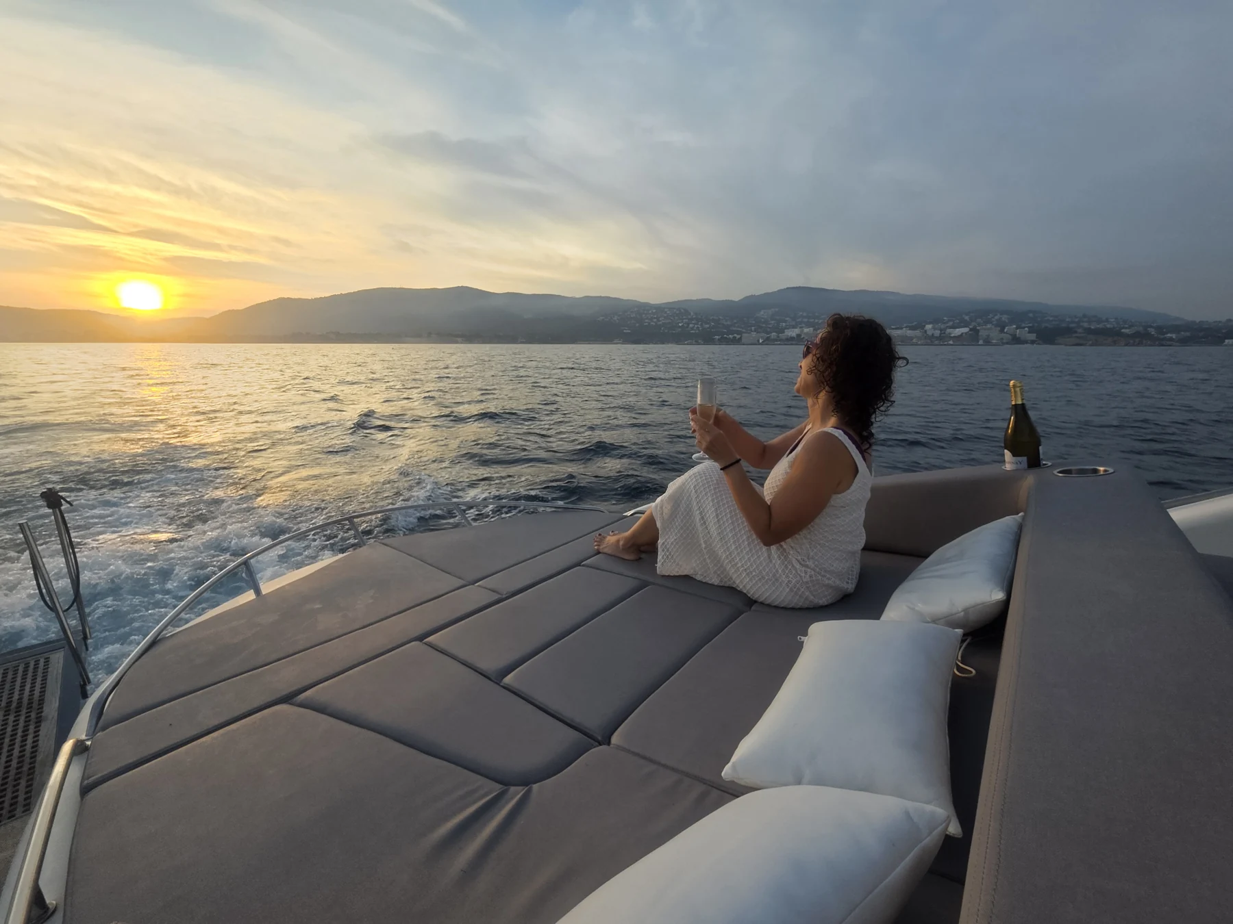 Eine Frau genießt ein Getränk und den Sonnenuntergang an Deck